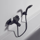 Black shower faucet set on a white tiled wall